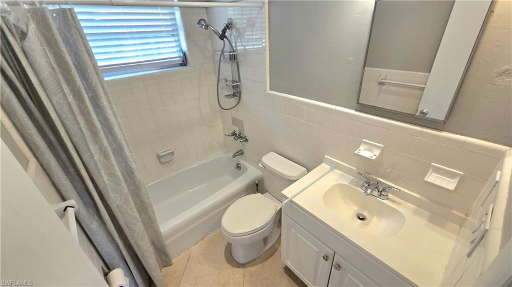 5529 Hardee Street Naples, FL 34113 - Photo 12 of 17 Bathroom #2 featuring a bathtub with shower fixture, white subway tile surround, white vanity with integrated sink, and an unframed mirror