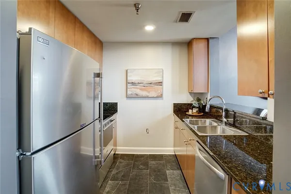 a kitchen with stainless steel appliances granite countertop a refrigerator a sink and a stove