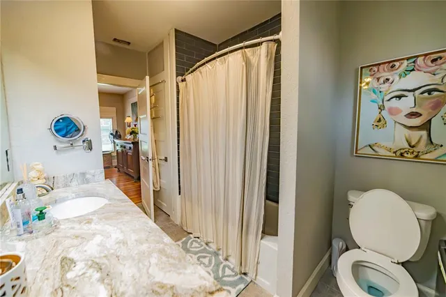 a bathroom with a granite countertop sink a toilet and shower