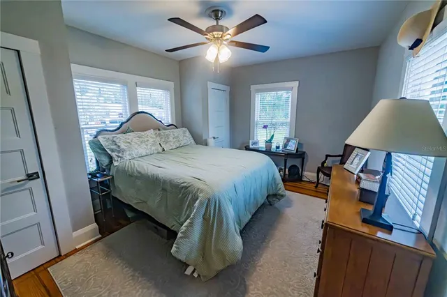 a bedroom with a bed and a lamp on dresser next to a window