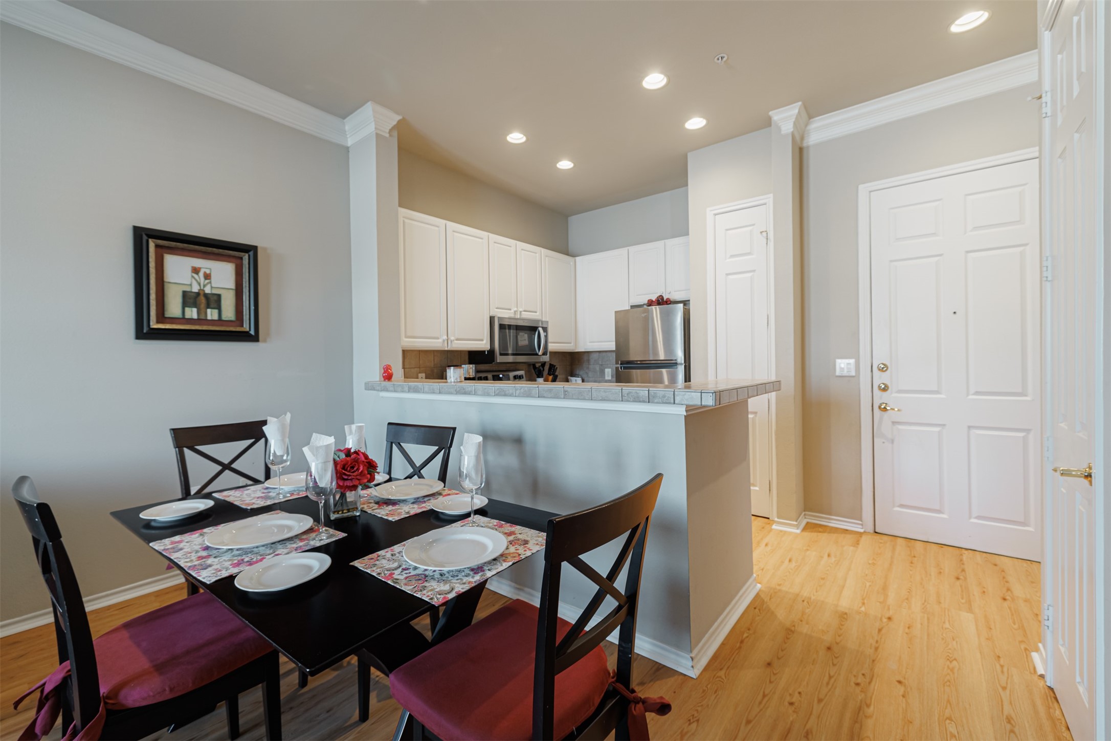 Charming kitchen and dining area featuring modern stainless steel appliances, crisp white cabinetry, and a cozy dining nook with elegant place settings, perfect for intimate gatherings.