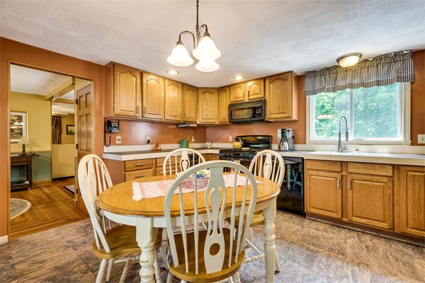 4 Old Providence Road Sutton, MA 01590 - Photo 5 of 30 a kitchen with stainless steel appliances granite countertop a sink a stove a refrigerator cabinets and a dining table with wooden floor