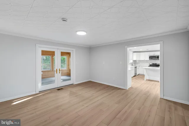 an empty room with wooden floor fan and windows