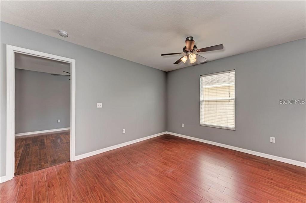 10267 Newminster Loop Ruskin, FL 33573 - Photo 12 of 38 wooden floor in an empty room with a window