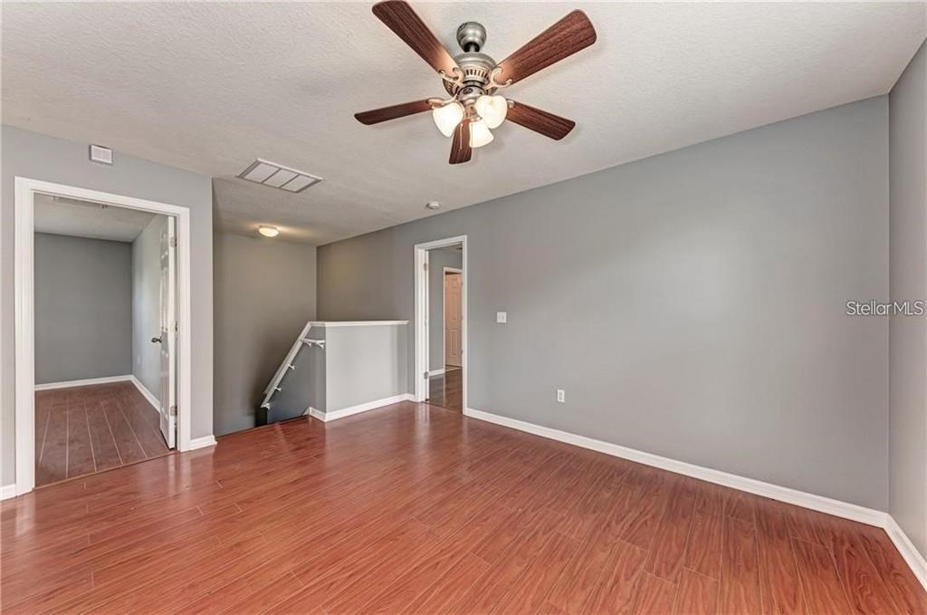 10267 Newminster Loop Ruskin, FL 33573 - Photo 13 of 38 an empty room with wooden floor and a ceiling fan