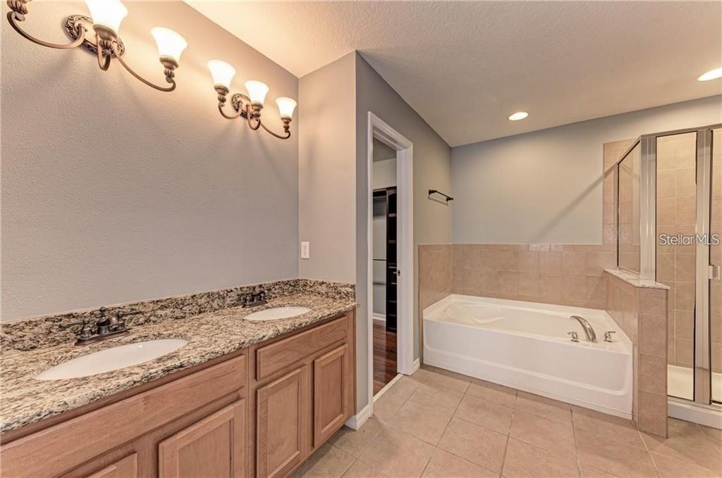 10267 Newminster Loop Ruskin, FL 33573 - Photo 18 of 38 a bathroom with a granite countertop sink a toilet and bathtub