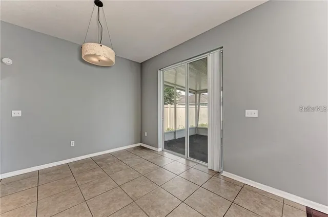 a view of an empty room with window and chandelier fan