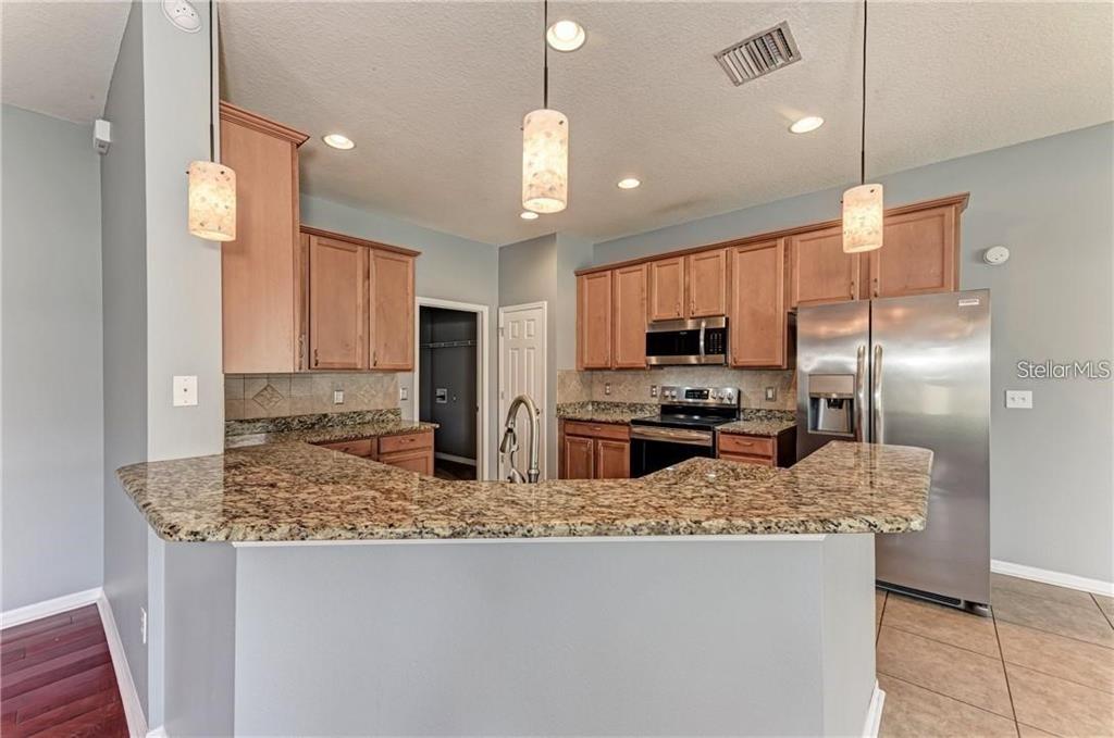 10267 Newminster Loop Ruskin, FL 33573 - Photo 7 of 38 a kitchen with stainless steel appliances granite countertop a sink refrigerator and microwave