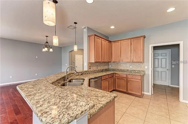 a kitchen with kitchen island granite countertop a sink a stove and cabinets