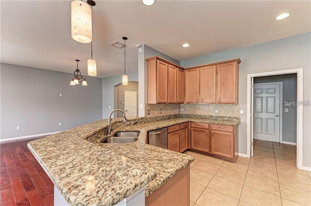 10267 Newminster Loop Ruskin, FL 33573 - Photo 8 of 38 a kitchen with kitchen island granite countertop a sink a stove and cabinets