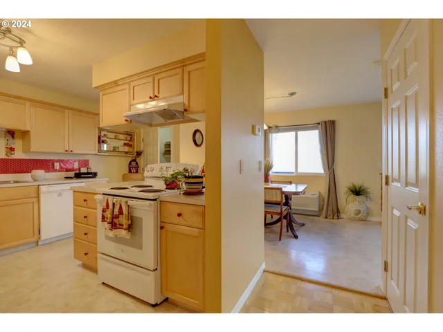 a kitchen that has a lot of white cabinets and stainless steel appliances