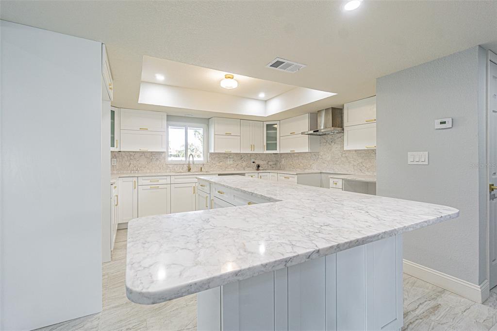 6370 Conniewood Square New Port Richey, FL 34653 - Photo 5 of 27 a large white kitchen with kitchen island a sink stove and white cabinets