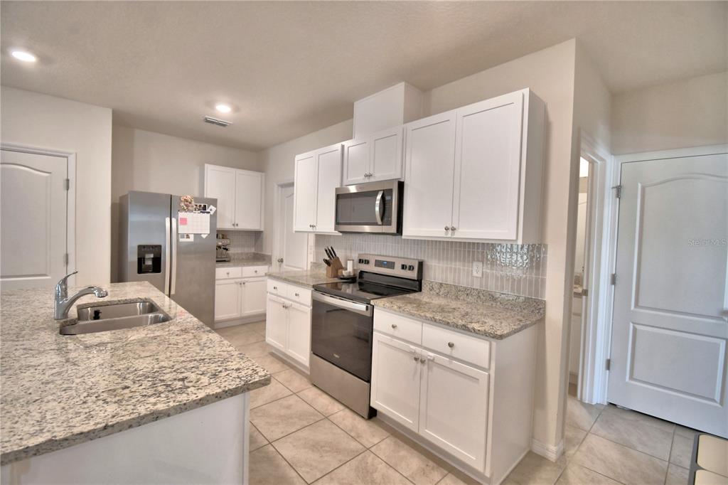 2839 Moulin Road Davenport, FL 33837 - Photo 16 of 75 a kitchen with granite countertop a sink stove and refrigerator