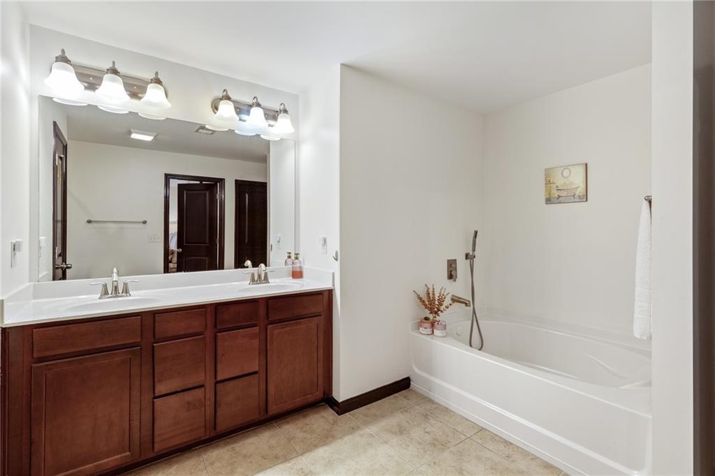 4430 Cedar Bridge Walk Suwanee, GA 30024 - Photo 23 of 29 a bathroom with a tub a sink double vanity and mirror