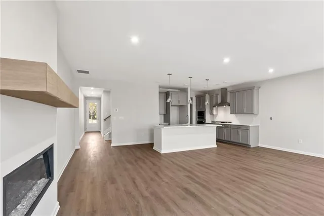 a living room with stainless steel appliances kitchen island wooden floors and white cabinets