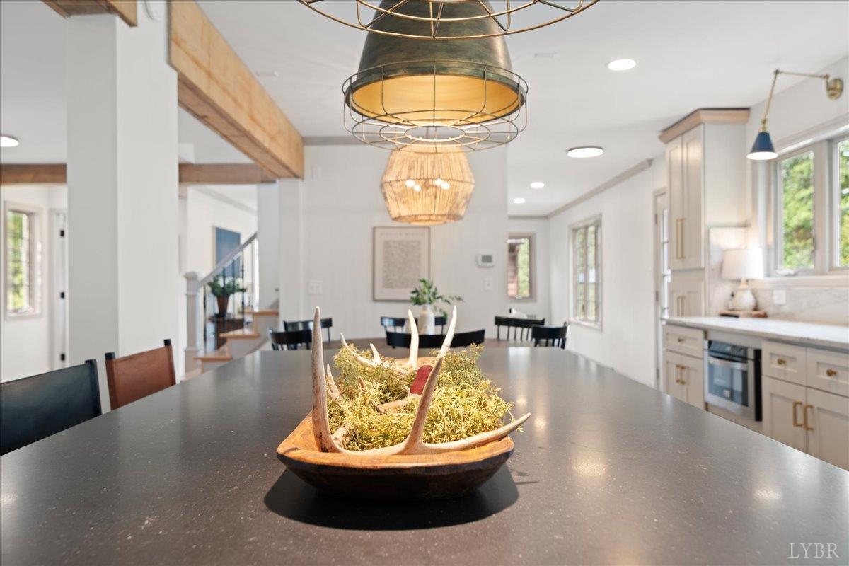 181 Mobley Mountain Road Amherst, VA 24521 - Photo 31 of 98 a living room with dining table a chandelier a large window and potted plants