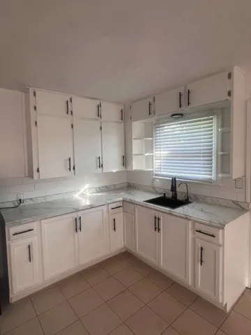 a kitchen with granite countertop stainless steel appliances white cabinets sink and a dishwasher