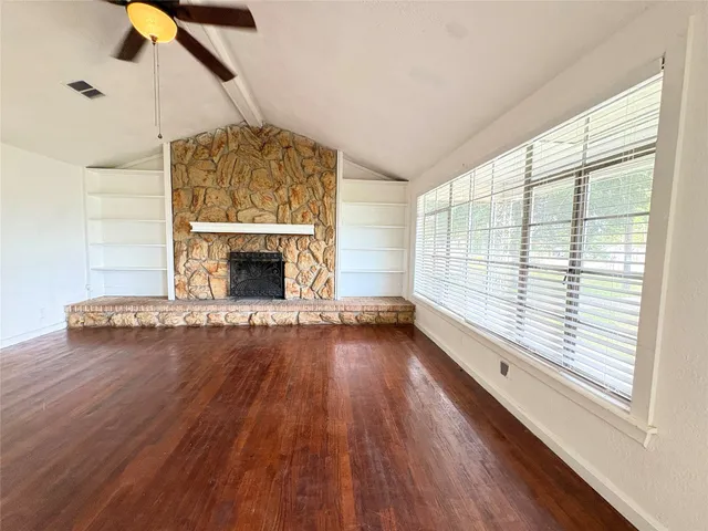 wooden floor fireplace and windows in an empty room