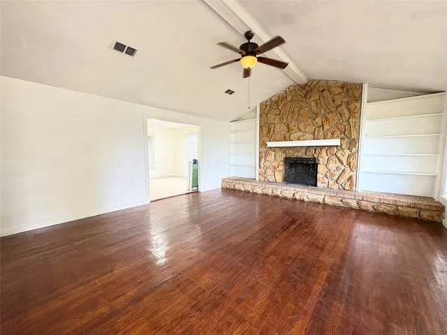 a view of an empty room with wooden floor fireplace and a window