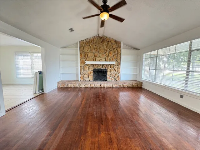an empty room with fireplace wooden floor and windows