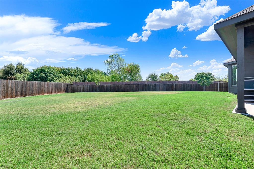 7640 Rhyner Way Fort Worth, TX 76137 - Photo 25 of 40 Expansive backyard featuring a meticulously manicured lawn, mature tree line, and wooden privacy fencing