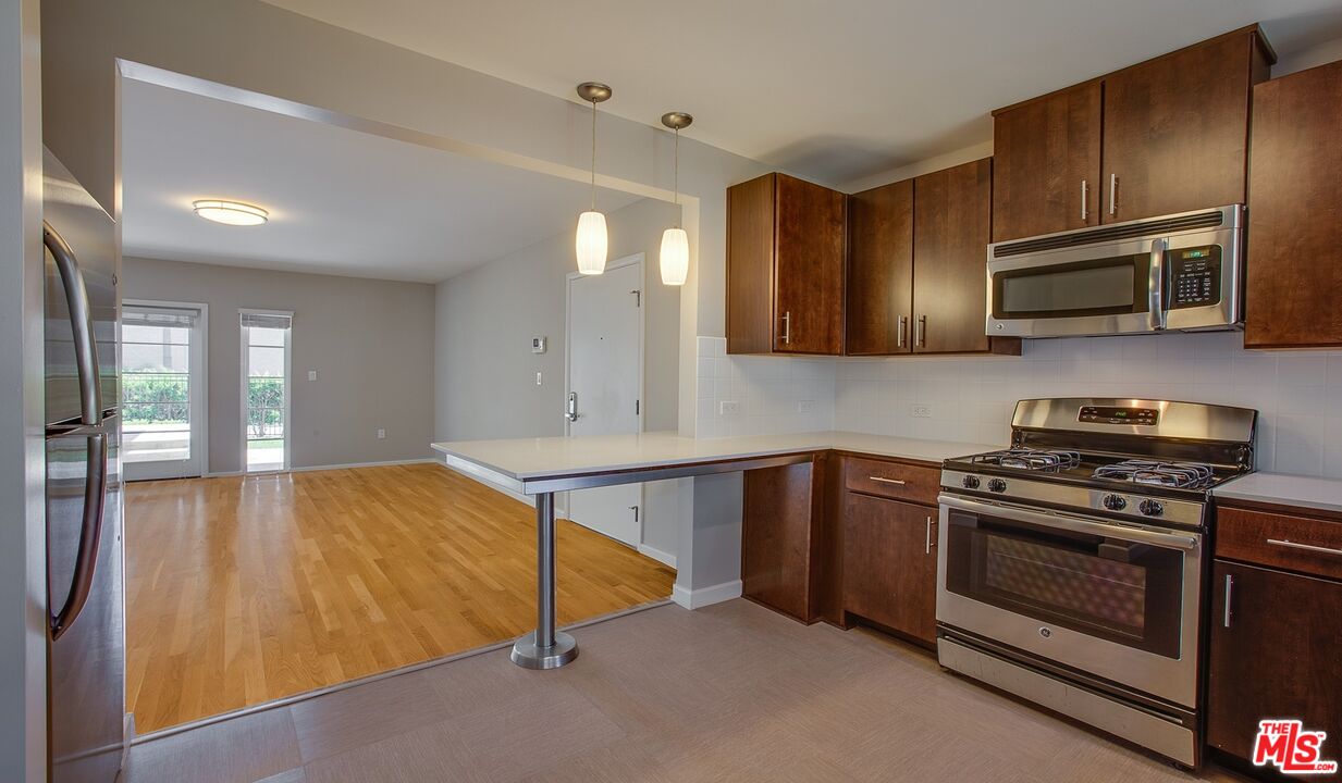 1012 Frederick Street, Unit 1 Venice, CA 90291 - Photo 3 of 10 a kitchen with stainless steel appliances wooden cabinets and a stove top oven
