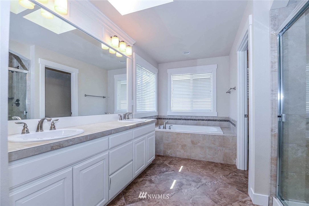 4423 220th Street Southeast Bothell, WA 98021 - Photo 17 of 24 a bathroom with a granite countertop sink a large mirror a bathtub and next to a window