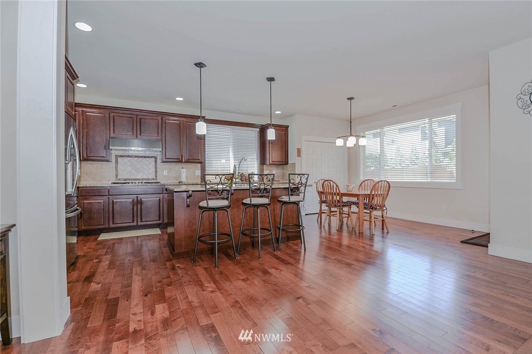 4423 220th Street Southeast Bothell, WA 98021 - Photo 5 of 24 a open kitchen with stainless steel appliances granite countertop a stove top oven a sink a dining table and chairs with wooden floor