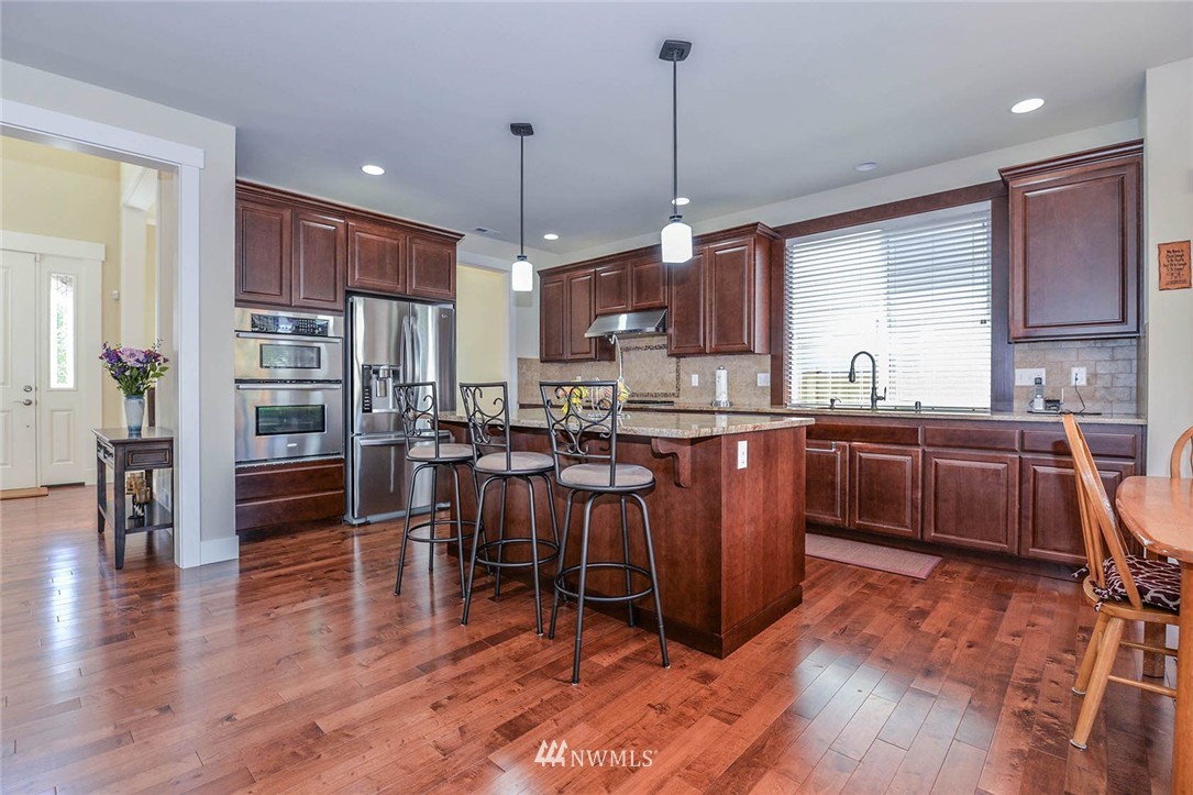 4423 220th Street Southeast Bothell, WA 98021 - Photo 6 of 24 a kitchen with stainless steel appliances granite countertop wooden cabinets a dining table and chairs