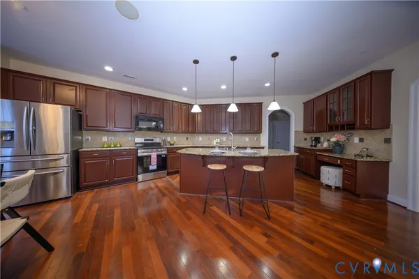 a kitchen with stainless steel appliances wooden floors wooden cabinets and a sink