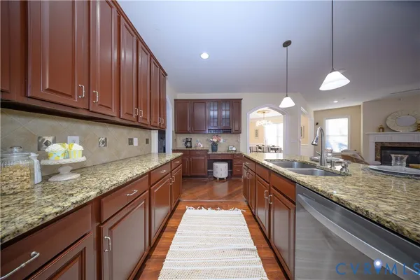 a open kitchen with granite countertop a sink dishwasher stove and cabinets with wooden floor