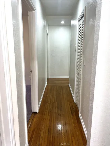 a view of a hallway with wooden floor and staircase