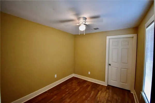 an empty room with wooden floor and fan