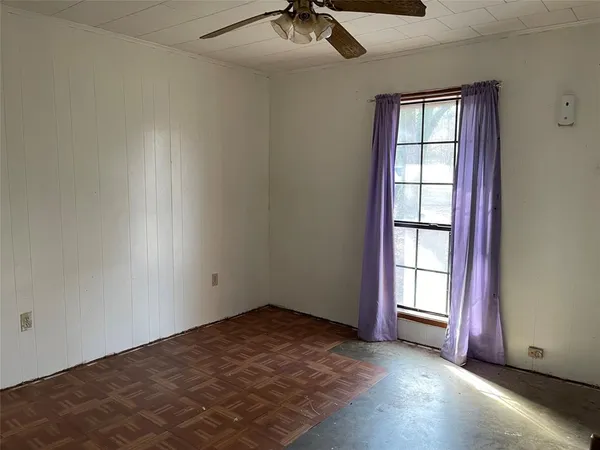 an empty room with windows and chandelier fan