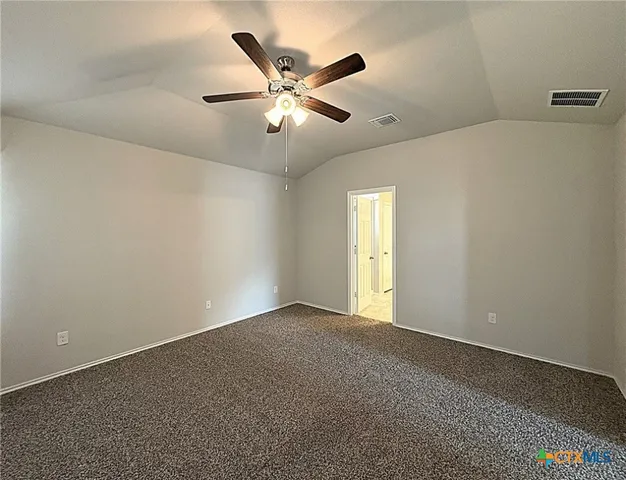 an empty room with chandelier fan and windows