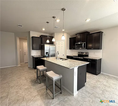 a large kitchen with stainless steel appliances kitchen island granite countertop a stove a sink a microwave and a refrigerator