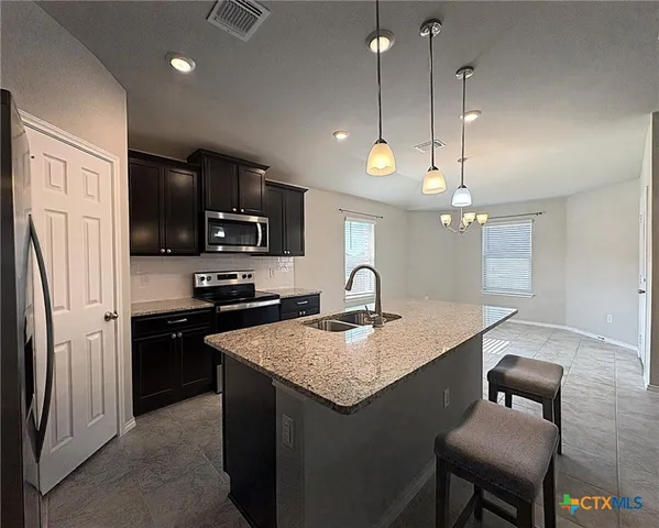 a kitchen with a sink a center island a stove cabinets and stainless steel appliances
