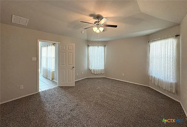 an empty room with windows and fan