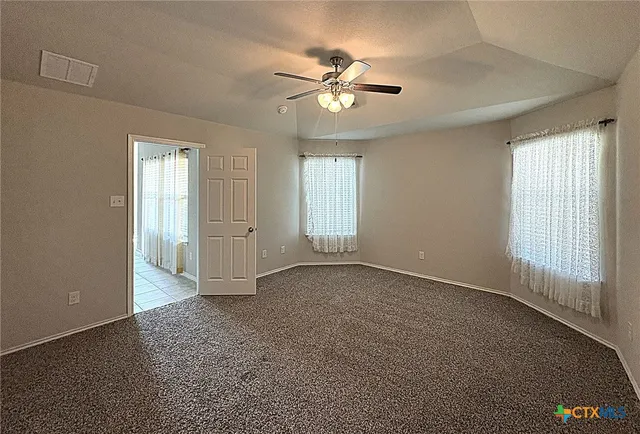 an empty room with windows and fan