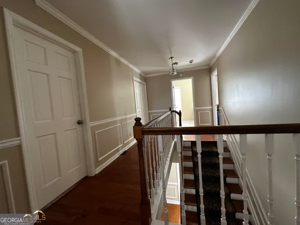 a view of a hallway with wooden floor and staircase