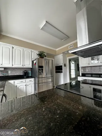 a kitchen with granite countertop a refrigerator and a stove top oven