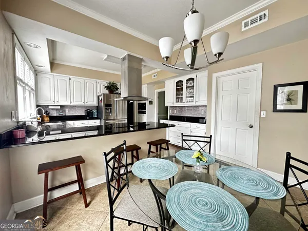 a kitchen with stainless steel appliances kitchen island granite countertop a stove a sink a dining table and chairs with wooden floor