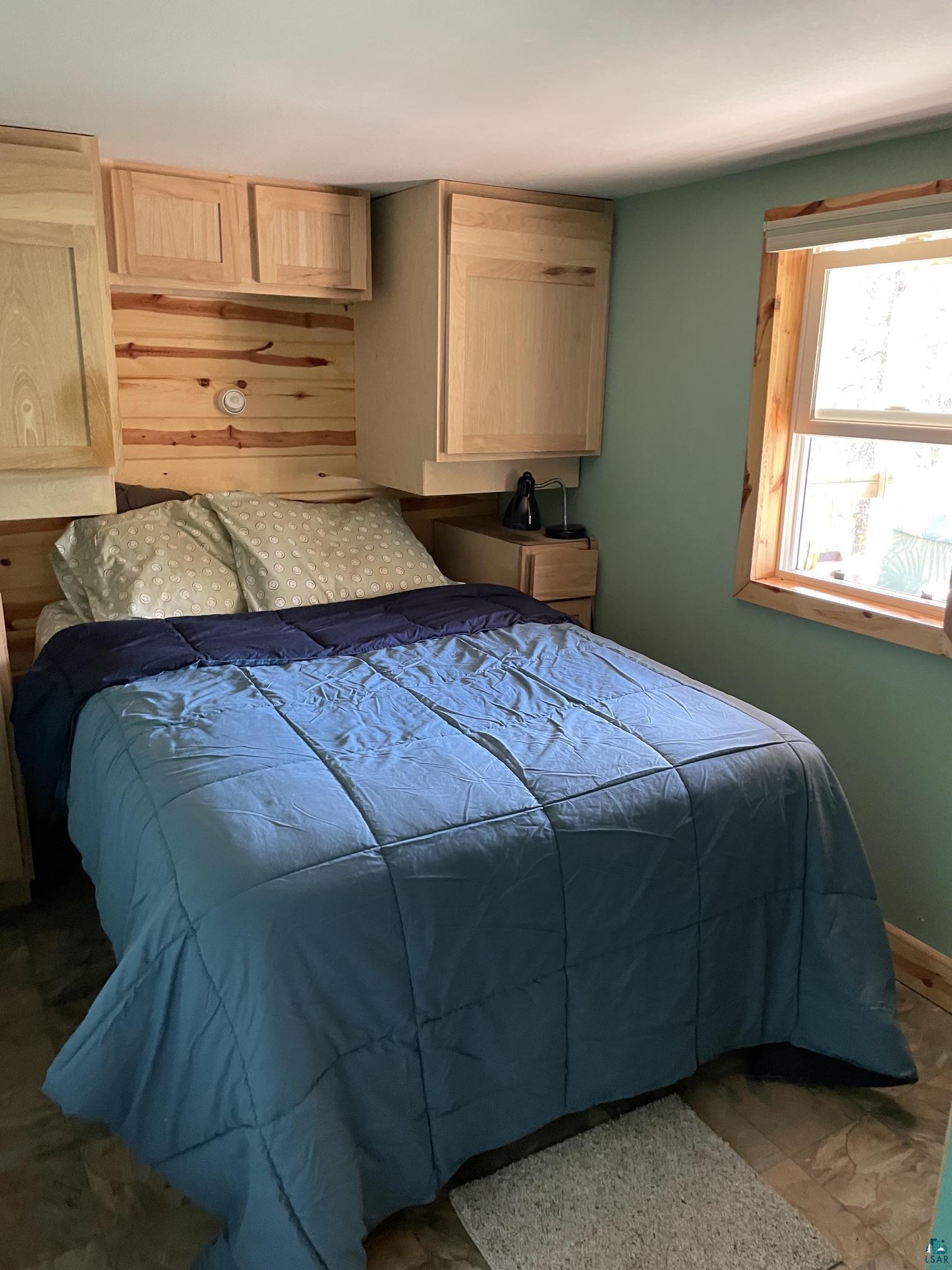 1152 Fernberg Road Ely, MN 55731 - Photo 8 of 24 Built-in natural wood cabinetry, wood panel accent wall, natural wood window trim, and painted wall finish