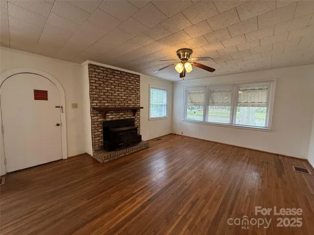 an empty room with windows fireplace and wooden floor