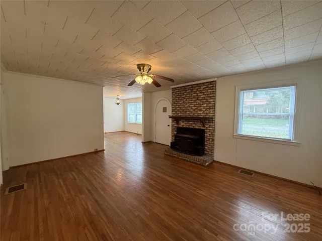 an empty room with wooden floor fireplace and window