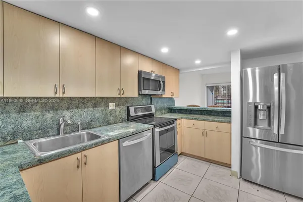 a kitchen with stainless steel appliances granite countertop a refrigerator a sink a stove with white cabinets