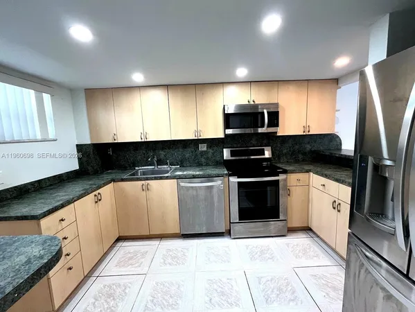 a kitchen with granite countertop a refrigerator and a sink
