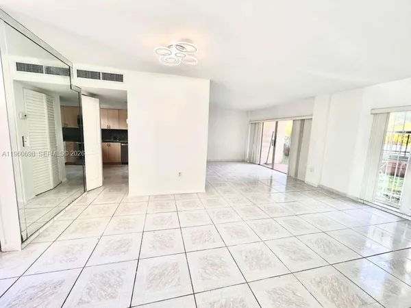 a view of an empty room with window and a kitchen