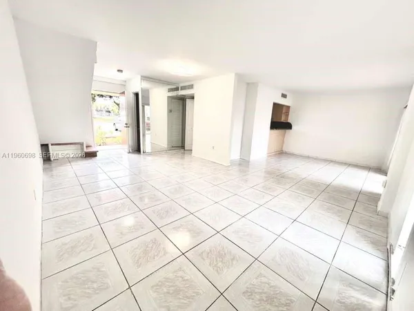 a view of a livingroom with kitchen space and a refrigerator