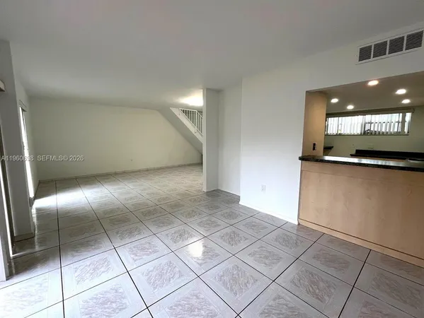 a view of a kitchen with a fridge and wooden floor